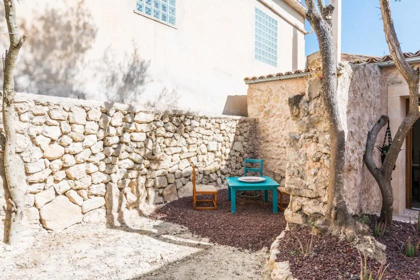 Una pequeña zona de estar al aire libre con una mesa y sillas junto a muros de piedra.