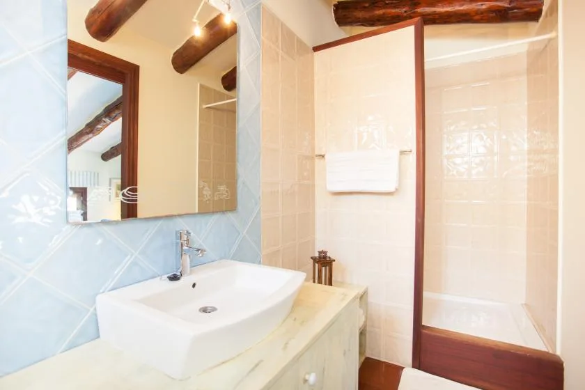 Un baño revestido de azulejos con lavabo y zona de ducha.