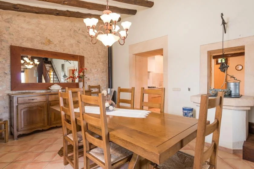 Un comedor rústico con una mesa larga de madera y sillas bajo una lámpara de araña.