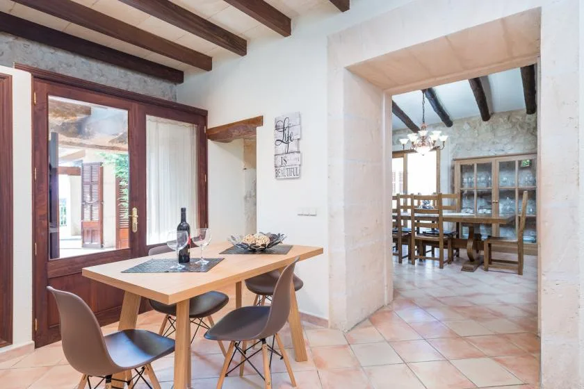 Un comedor con una mesa de madera está junto a una amplia abertura hacia otra habitación.