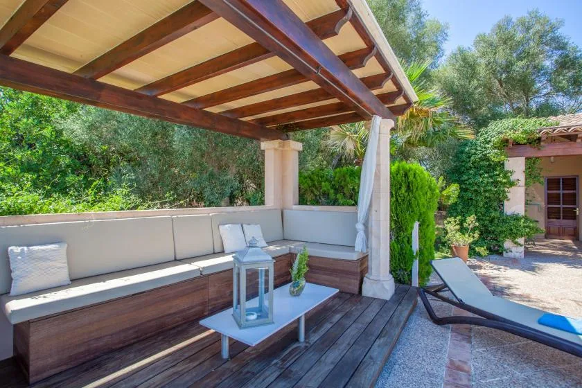 Un patio exterior cubierto tiene asientos incorporados junto a una piscina.