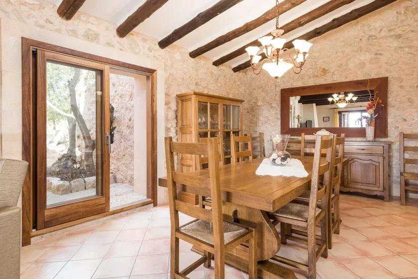 Un comedor rústico con una mesa y sillas de madera bajo vigas expuestas.
