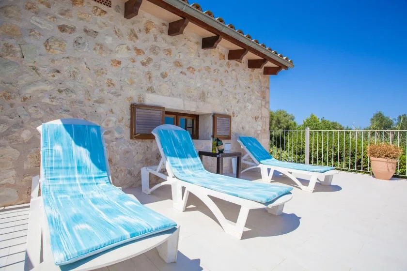 Una terraza soleada con asientos azules junto a un edificio revestido de piedra.