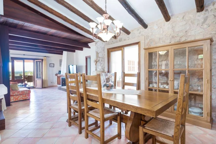 Un comedor con una mesa y sillas de madera bajo vigas de techo expuestas.