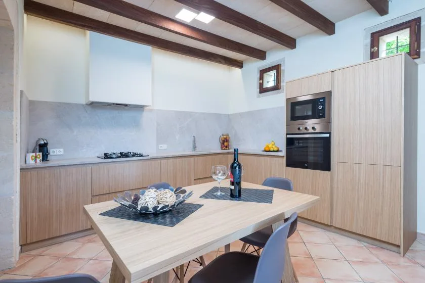 Una cocina luminosa con mesa de comedor y electrodomésticos integrados.
