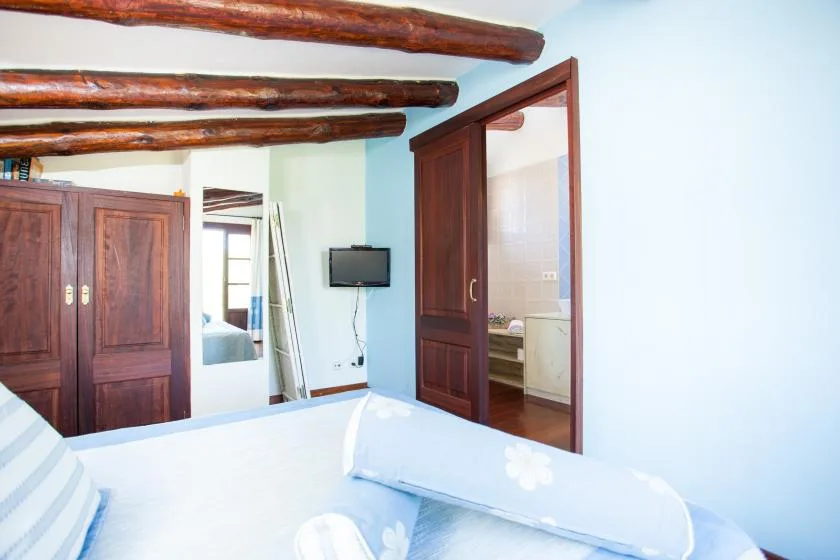 Un dormitorio con una cama, armarios de madera y una puerta abierta al baño.