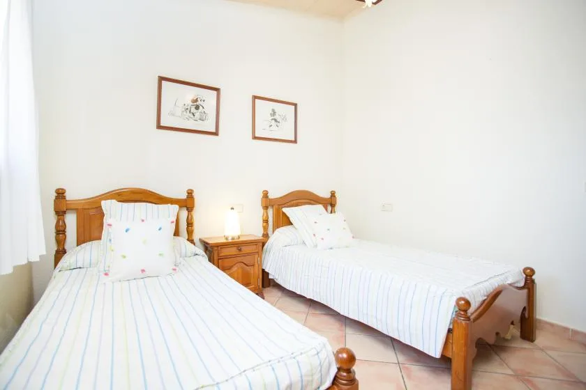 Un dormitorio con dos camas de madera y una pequeña mesita de noche.
