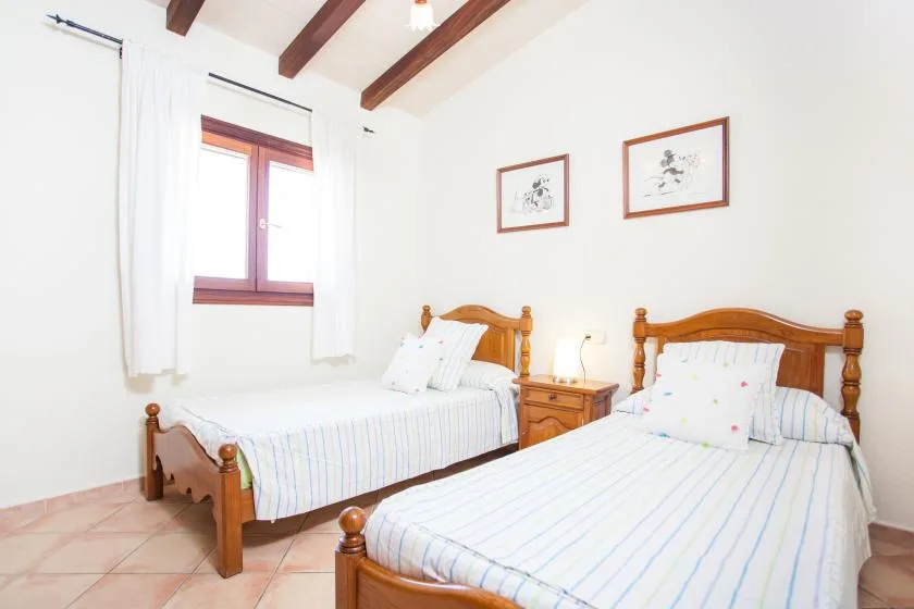 Un dormitorio luminoso con dos camas y cuadros en la pared.