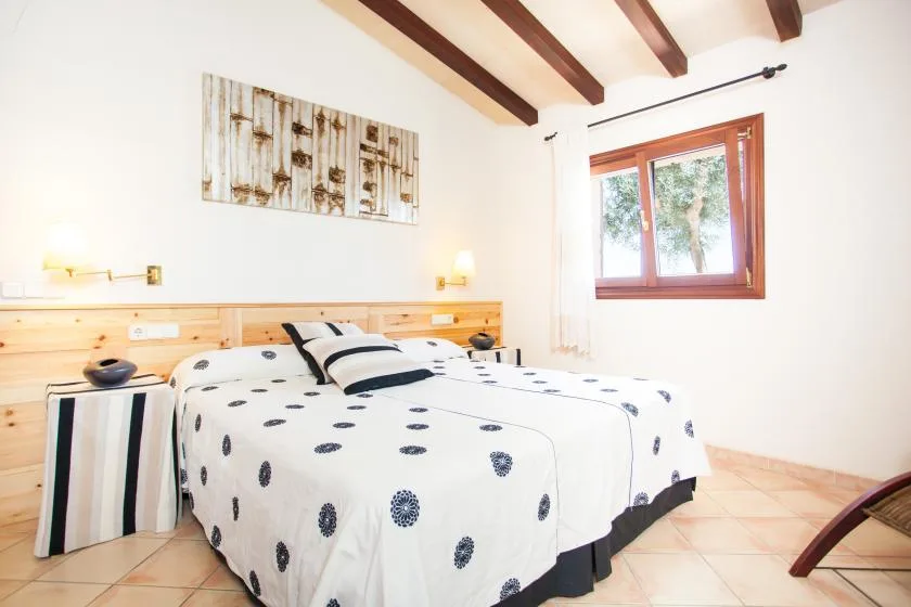 Un dormitorio con una cama cubierta de ropa blanca estampada con motivos oscuros.