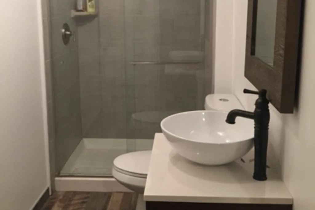 Un baño con un lavabo sobre encimera junto a una ducha de vidrio.
