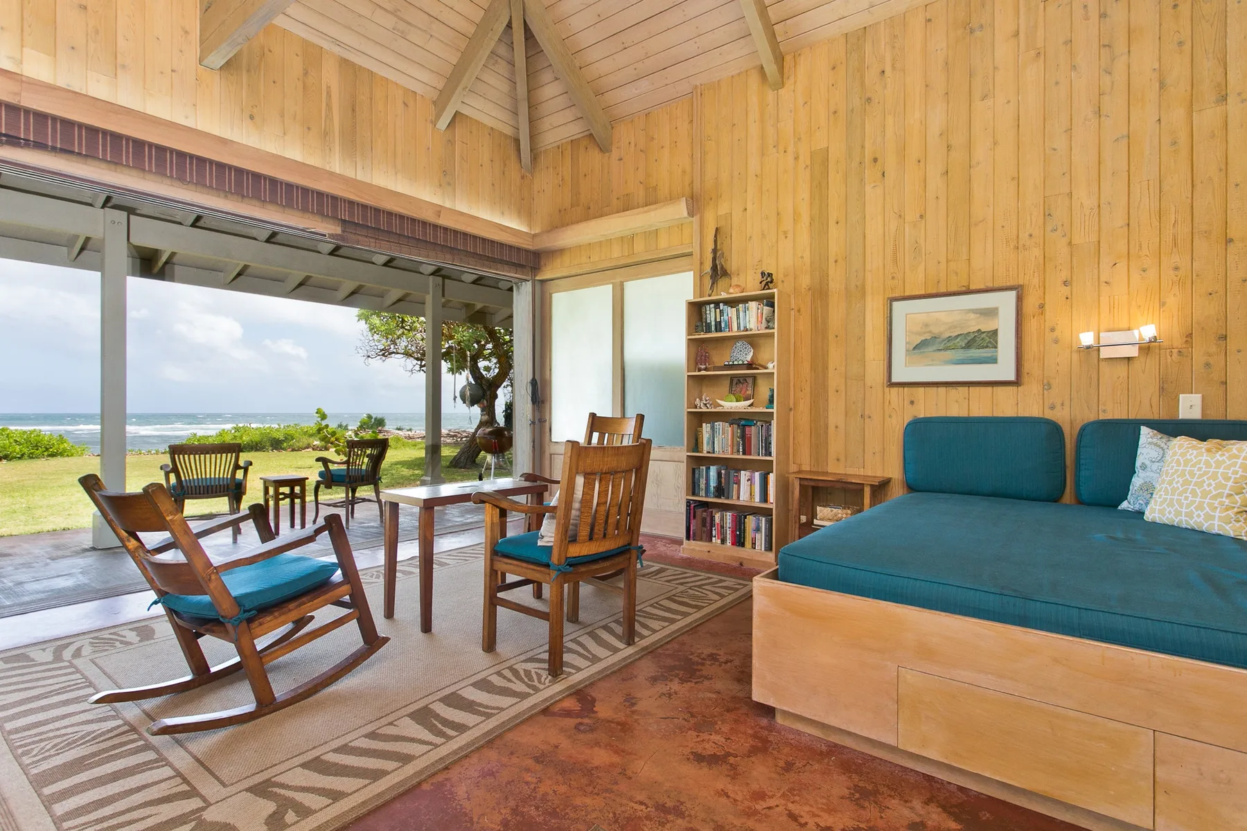 A wood-paneled living room opens onto a patio with ocean views.