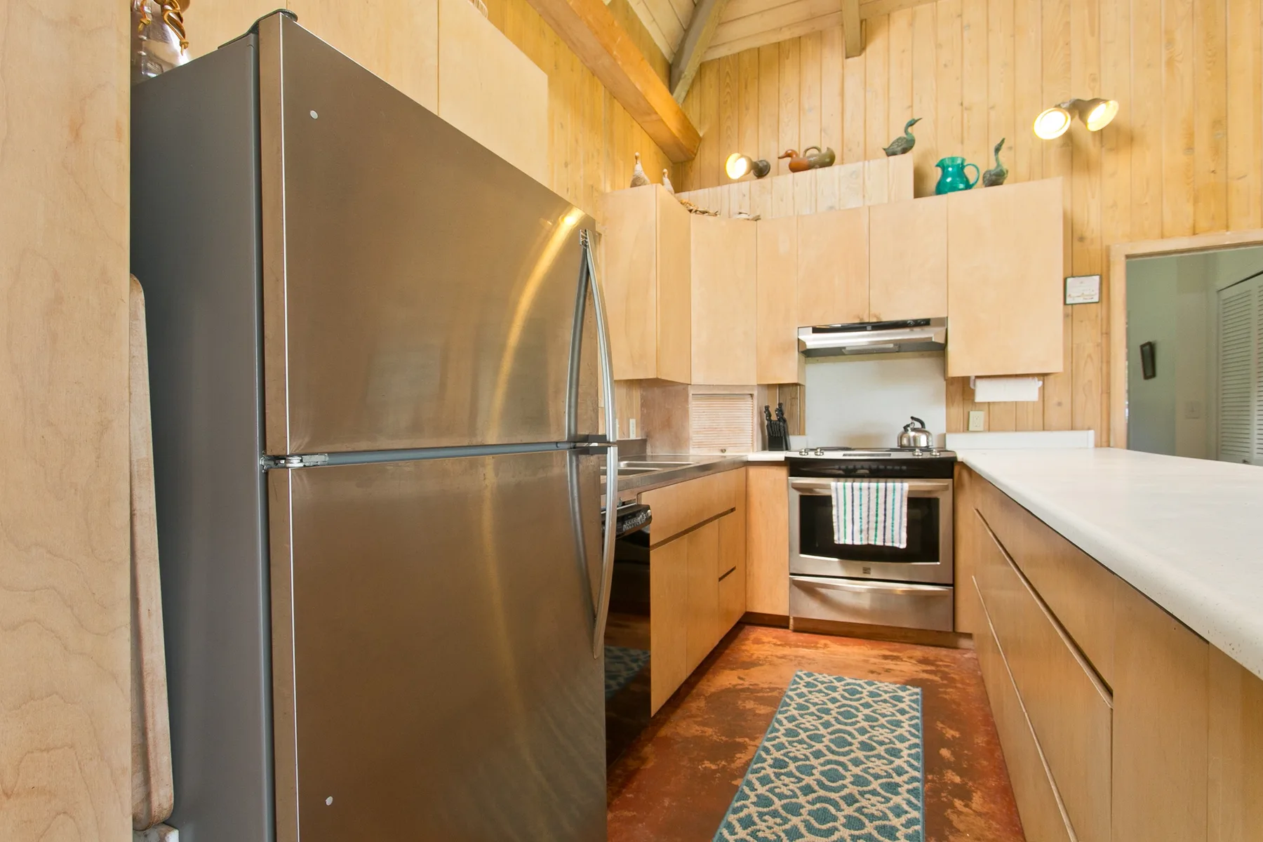 A wood-paneled kitchen has stainless steel appliances and a long countertop.