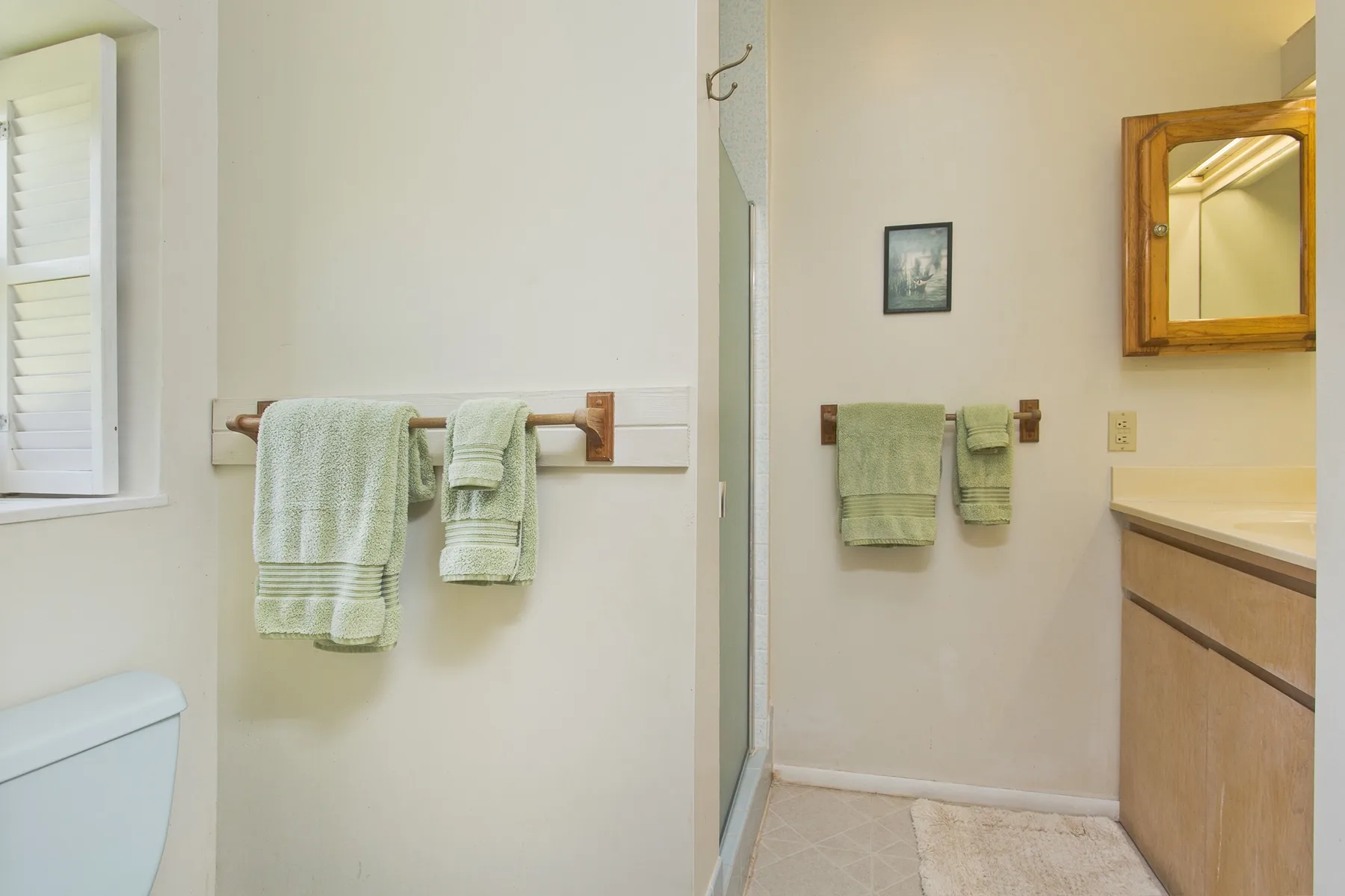 A bathroom with towels hanging on wall-mounted bars beside a vanity.