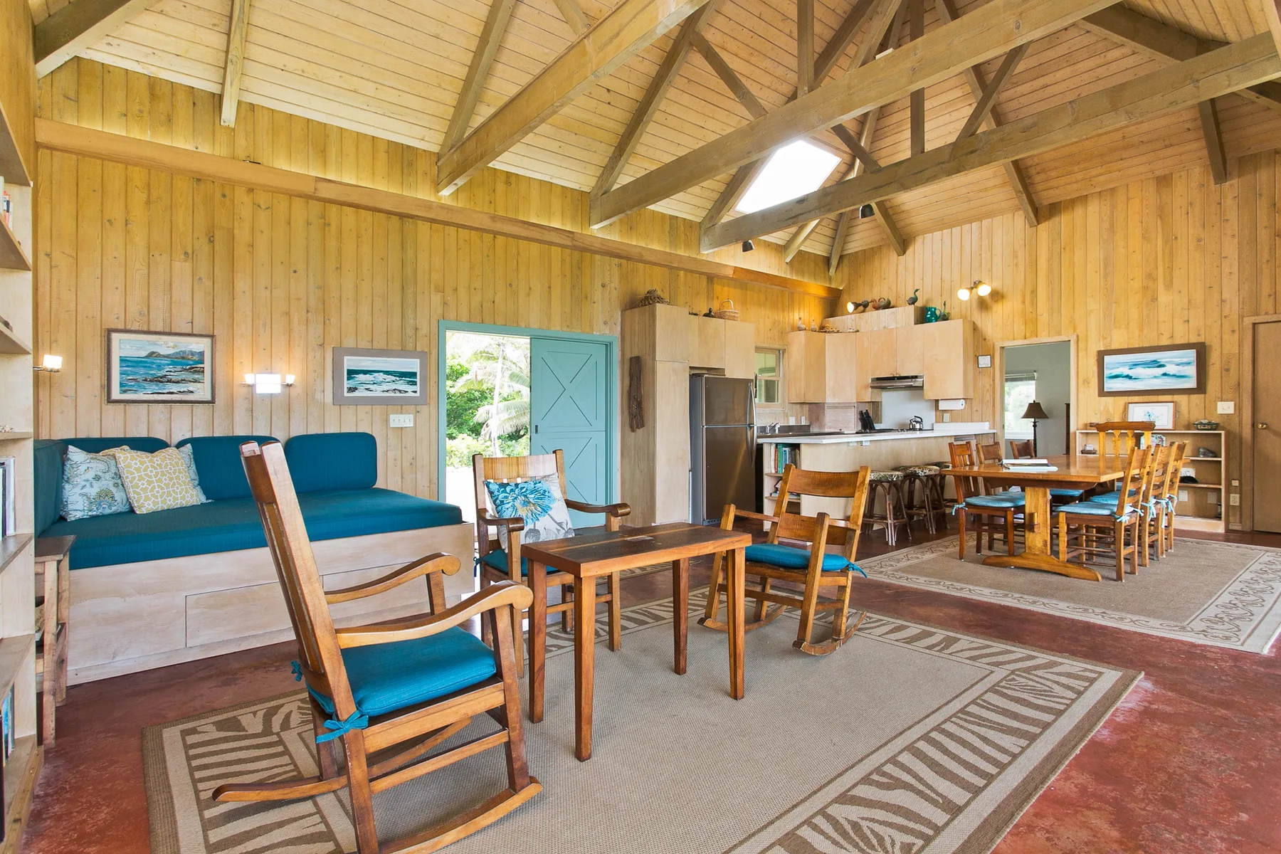 A wood-paneled living and dining area with seating, tables, and a high timber ceiling.