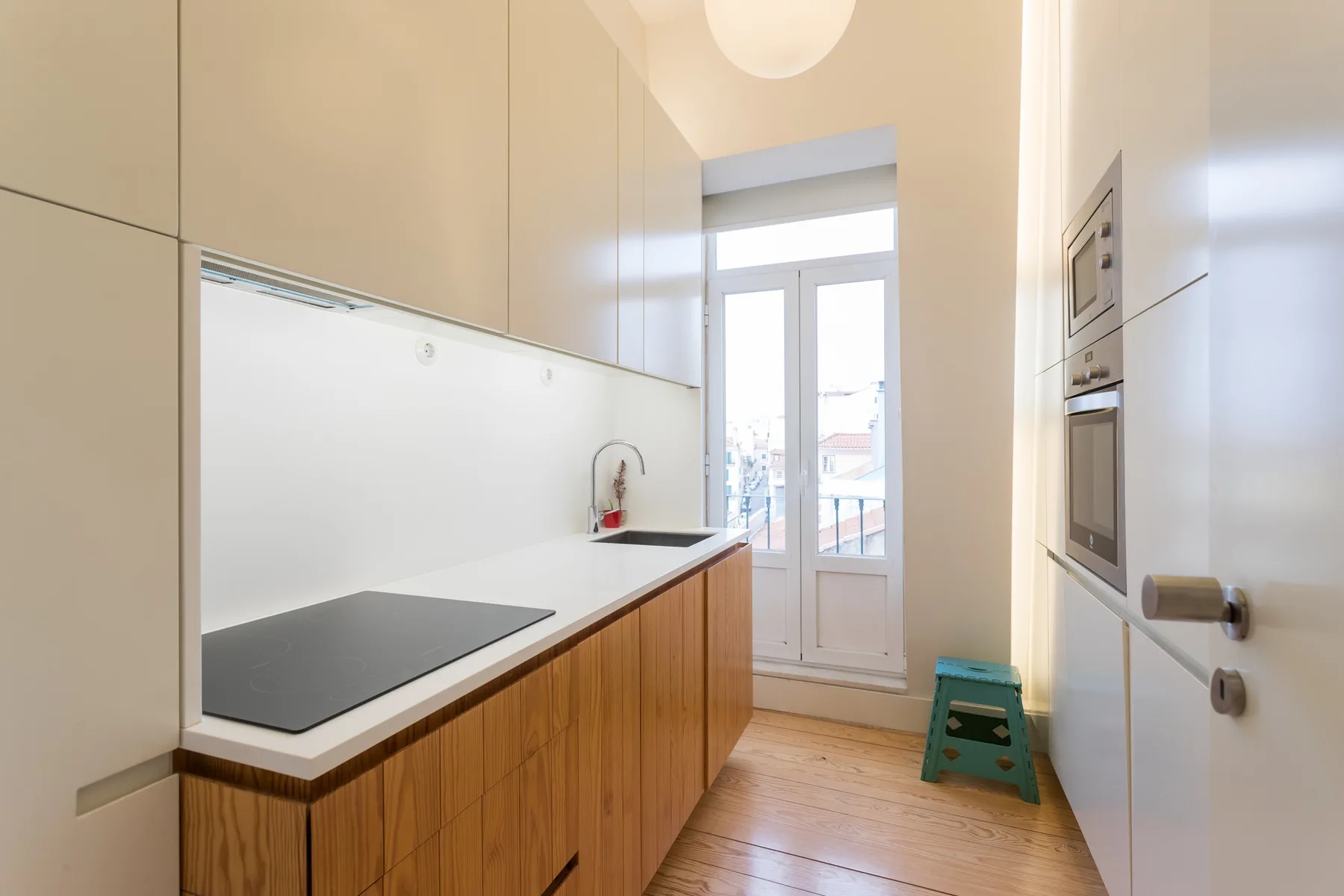 Una cocina luminosa con encimera, placa de cocina y ventanas altas.