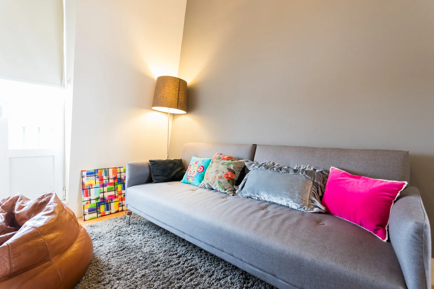 Una sala luminosa con asientos grises y cojines de colores.