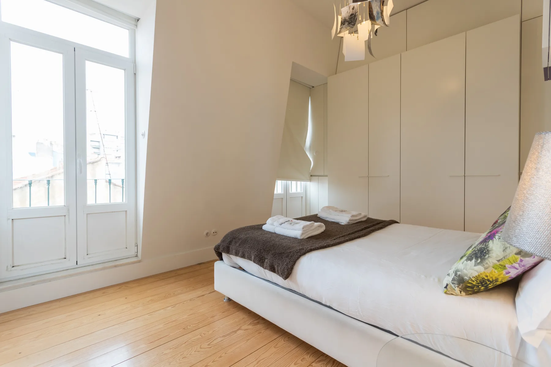 Un dormitorio con una cama junto a puertas acristaladas altas y armarios empotrados.