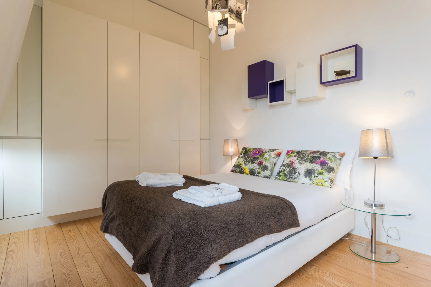 Un dormitorio con una cama cubierta con una manta oscura y cojines florales.