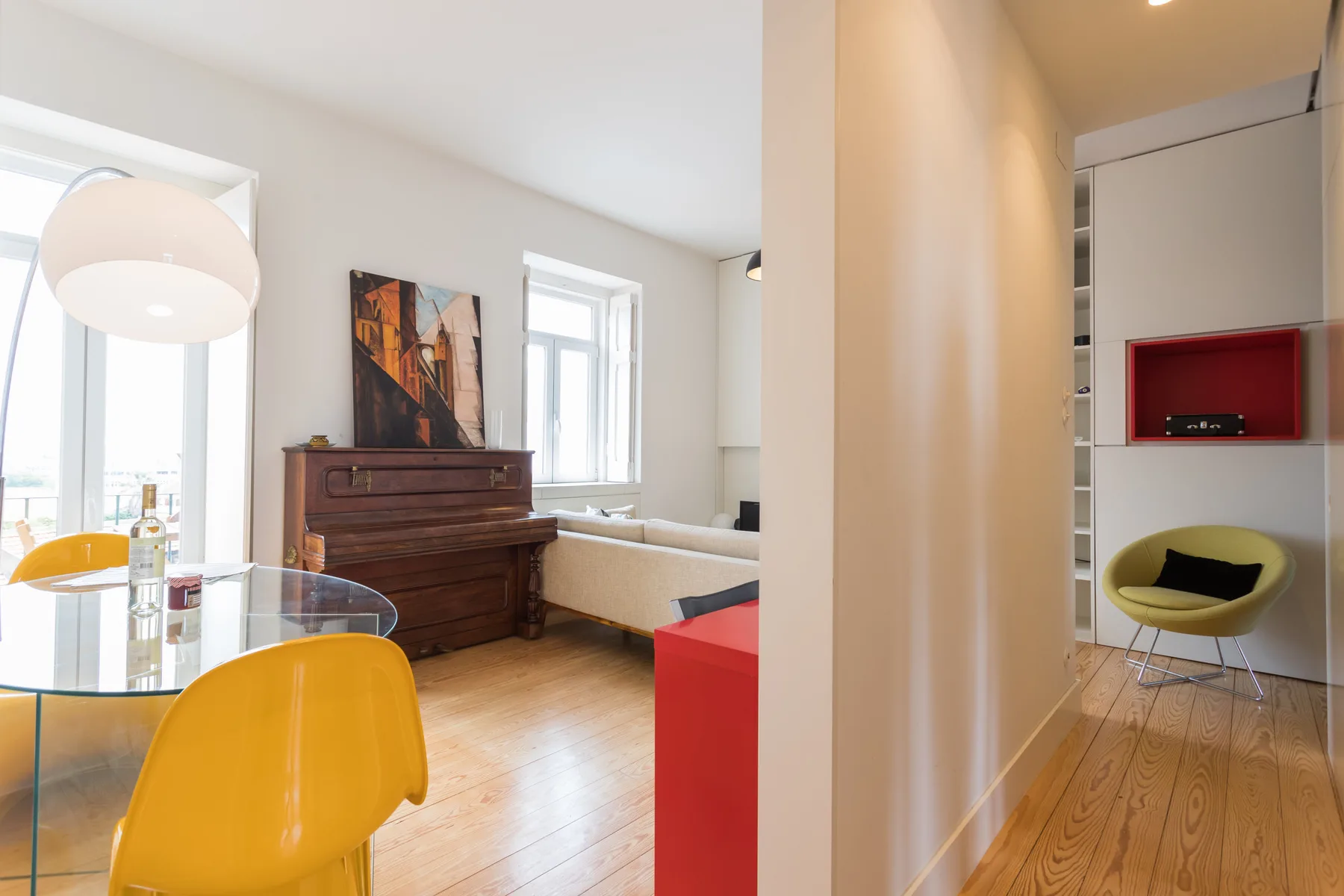 Una luminosa sala de estar con piano, mesa de comedor y asientos coloridos.