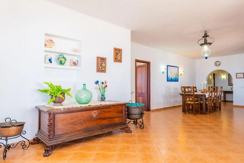 Un comedor luminoso con una mesa de madera y sillas junto a un aparador decorado.