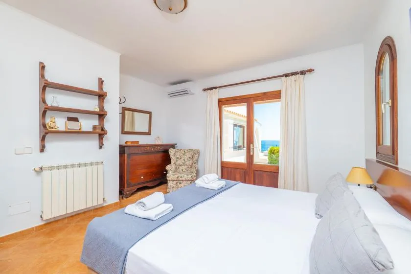 Un dormitorio luminoso con una cama bien hecha y una puerta de cristal que da a un balcón.