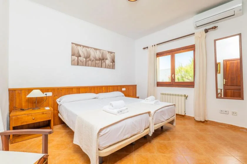 Un dormitorio con una cama bien tendida y una ventana con vistas a la vegetación.