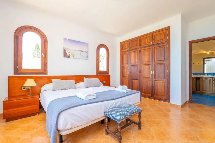 Un dormitorio con cama, cabecero de madera y armarios empotrados.