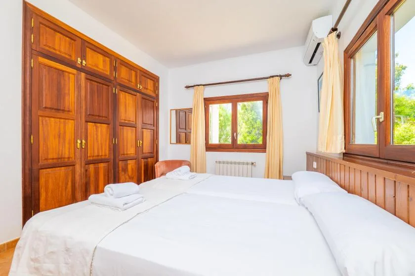 Un dormitorio luminoso con ropa de cama blanca y armarios empotrados de madera.