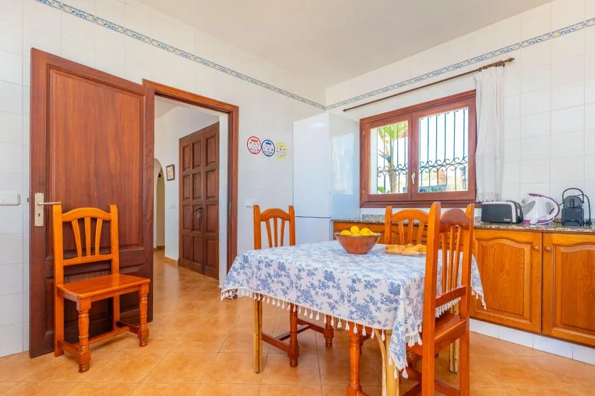 Comedor con paredes revestidas de azulejos, mesa, sillas de madera y ventana.