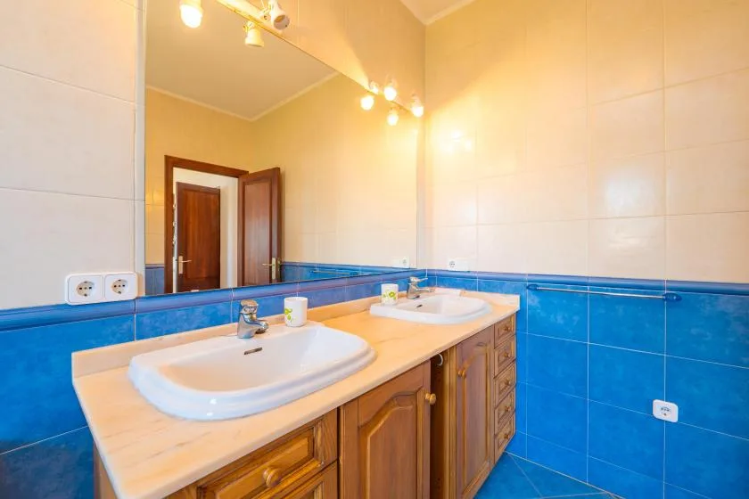 Un baño con dos lavabos, una encimera larga y un gran espejo de pared.