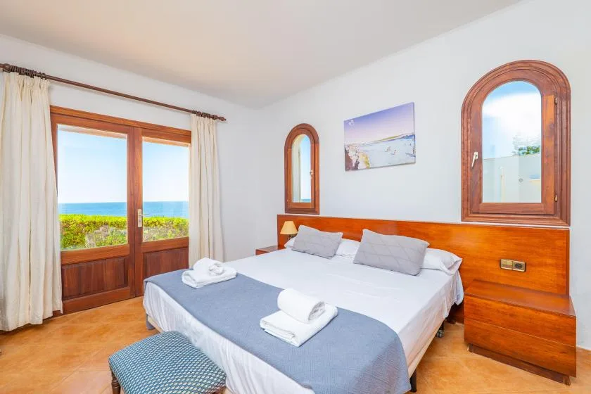 Un dormitorio con una cama bien arreglada y puertas de vidrio que dan a un balcón.