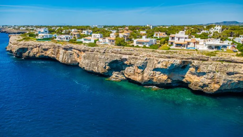 Un acantilado costero con casas se eleva sobre el mar azul.