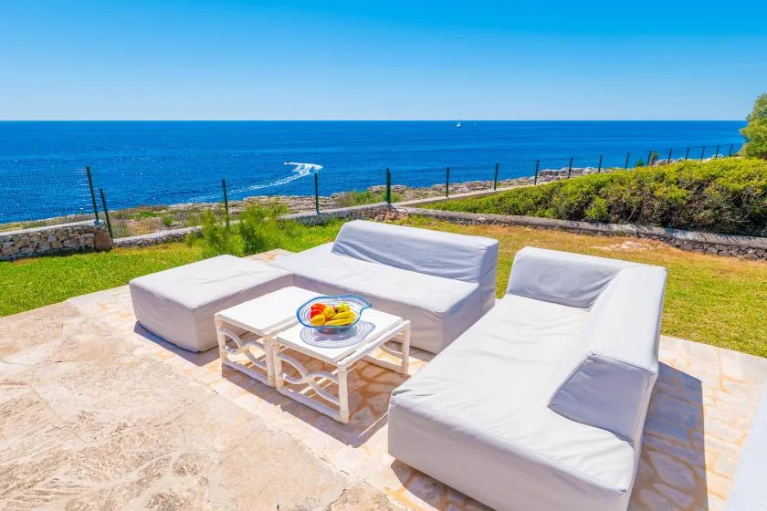 Una zona de estar al aire libre mira al mar, con una mesa baja entre los asientos.