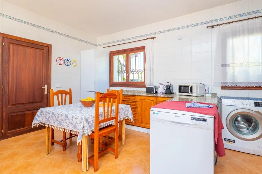 Una cocina y comedor con armarios de madera, una mesa y electrodomésticos de lavandería.