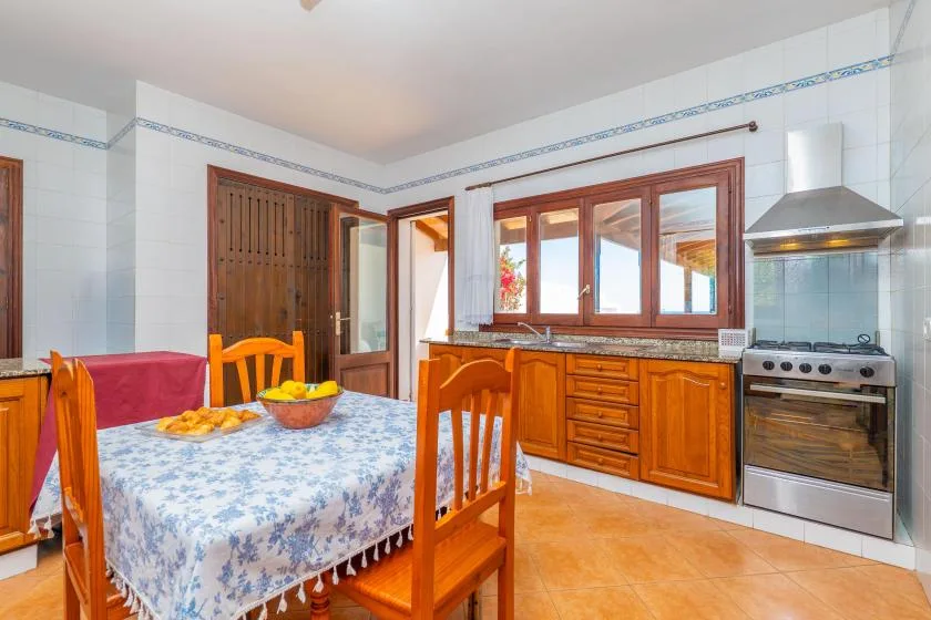 Una cocina y comedor con una mesa, armarios de madera y una estufa.