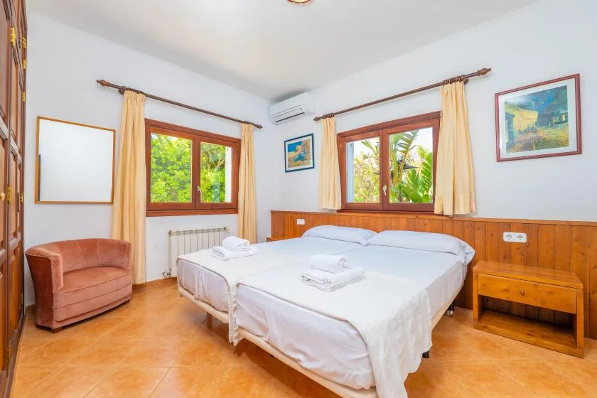 Un dormitorio con dos camas, ventanas con cortinas y una mesita de noche.