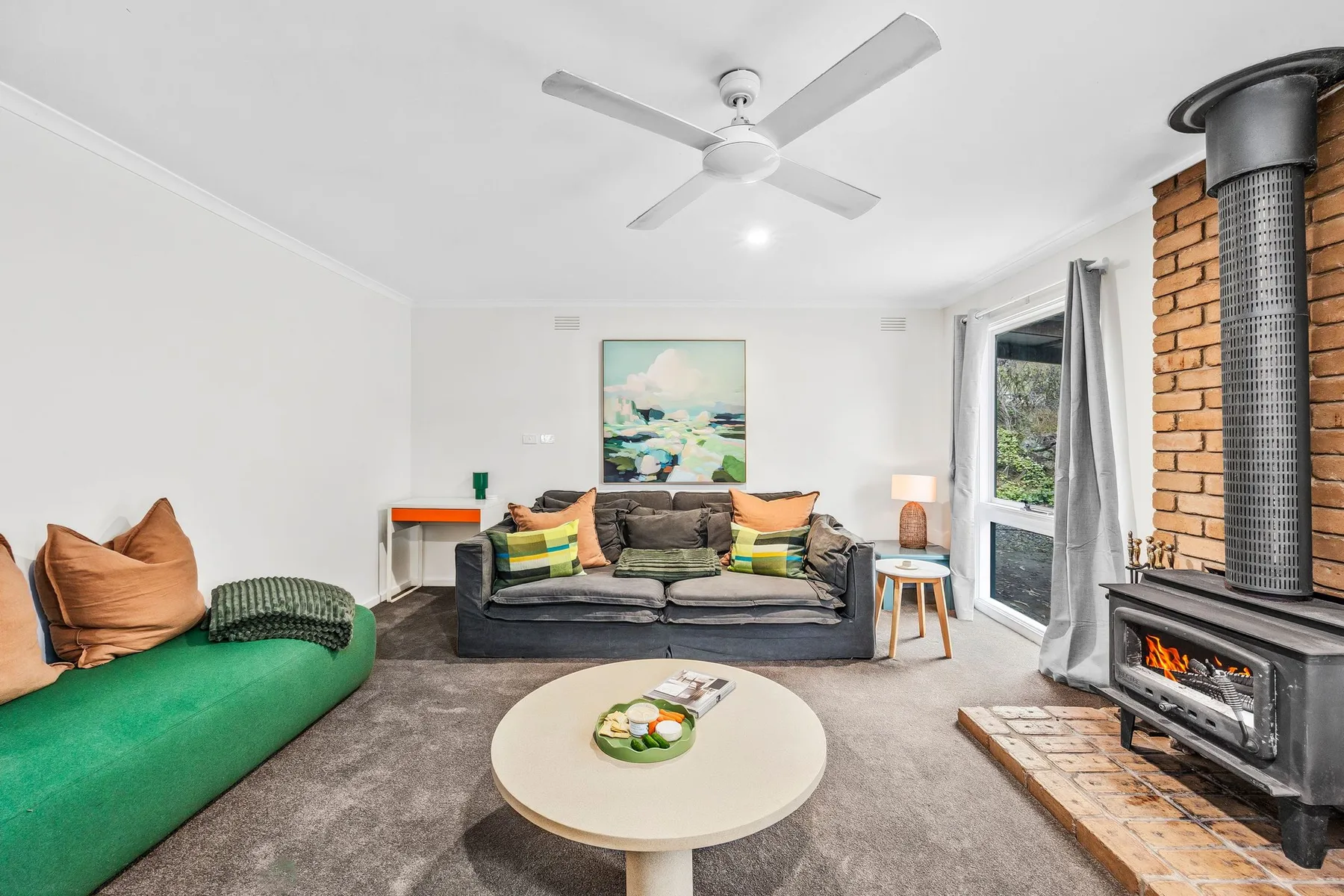 A living room with seating around a low coffee table and a wood-burning stove.