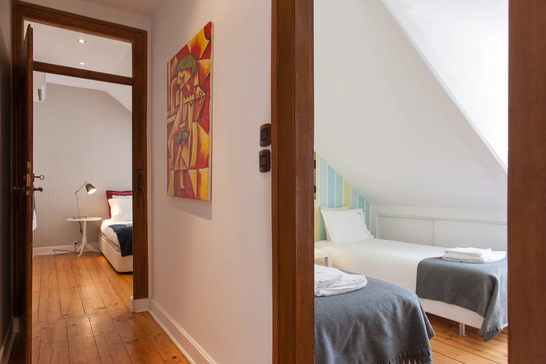 A hallway opens onto two bedrooms, with colorful artwork on the wall.