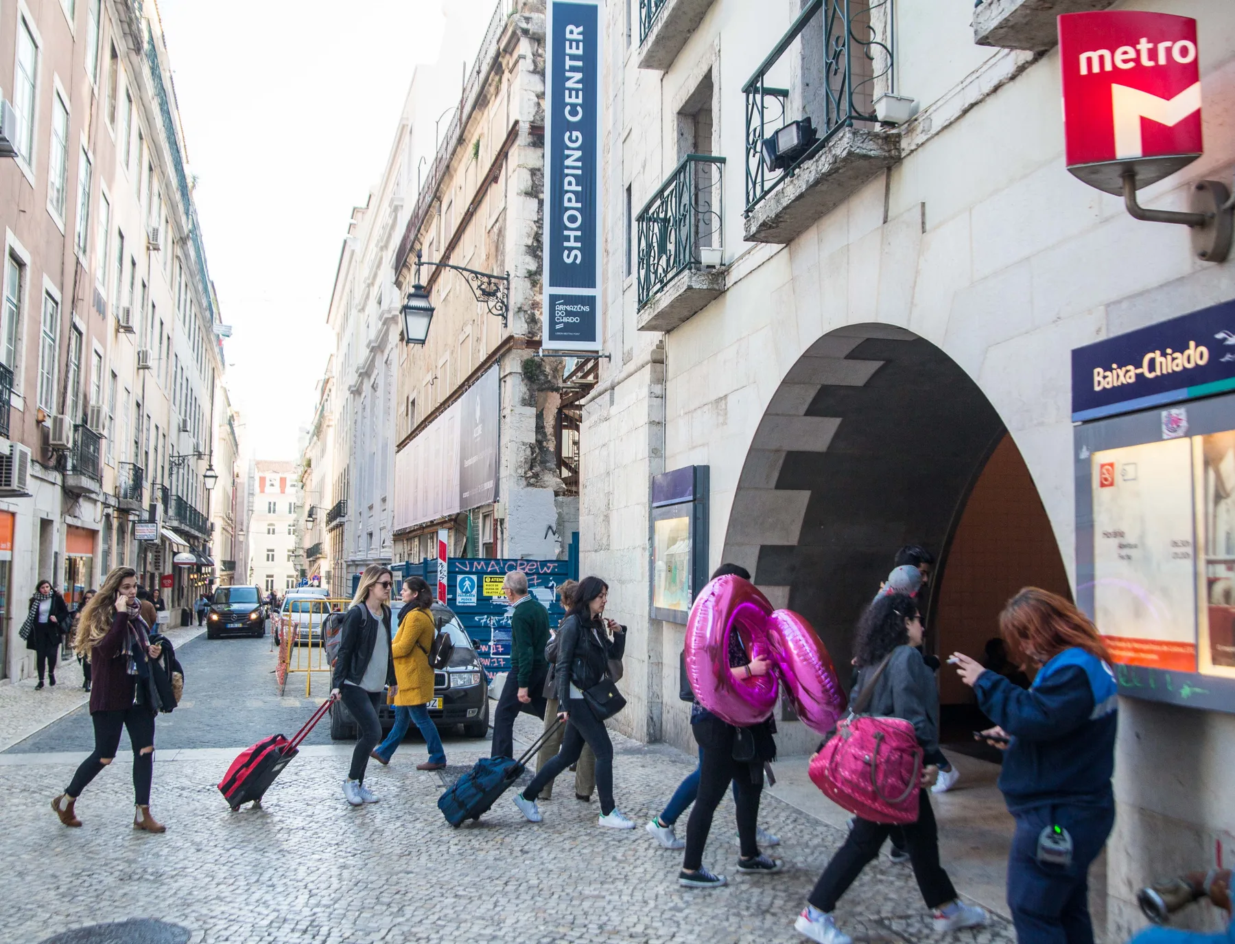 A busy city street with pedestrians beside a metro entrance.