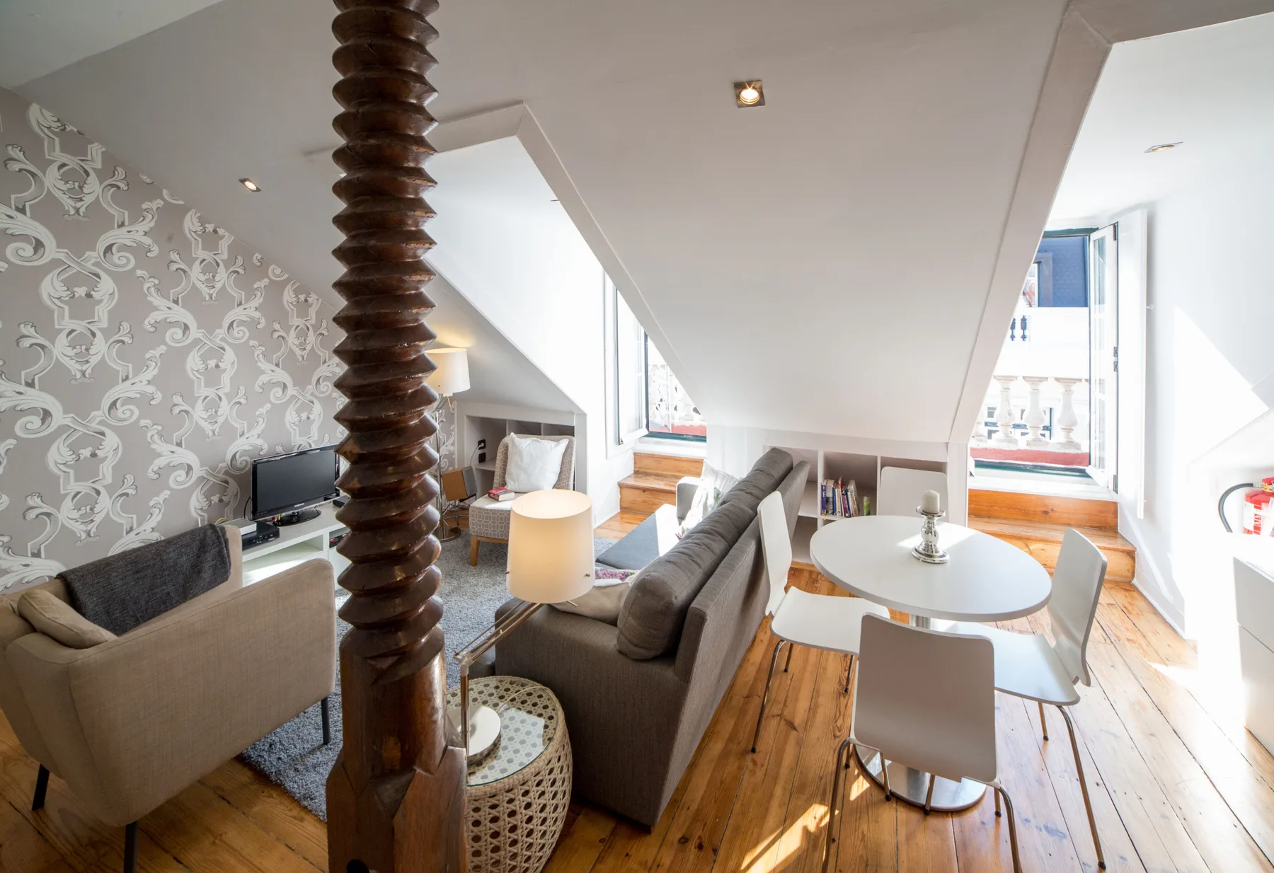 A bright living and dining area with seating and a table beside large windows.