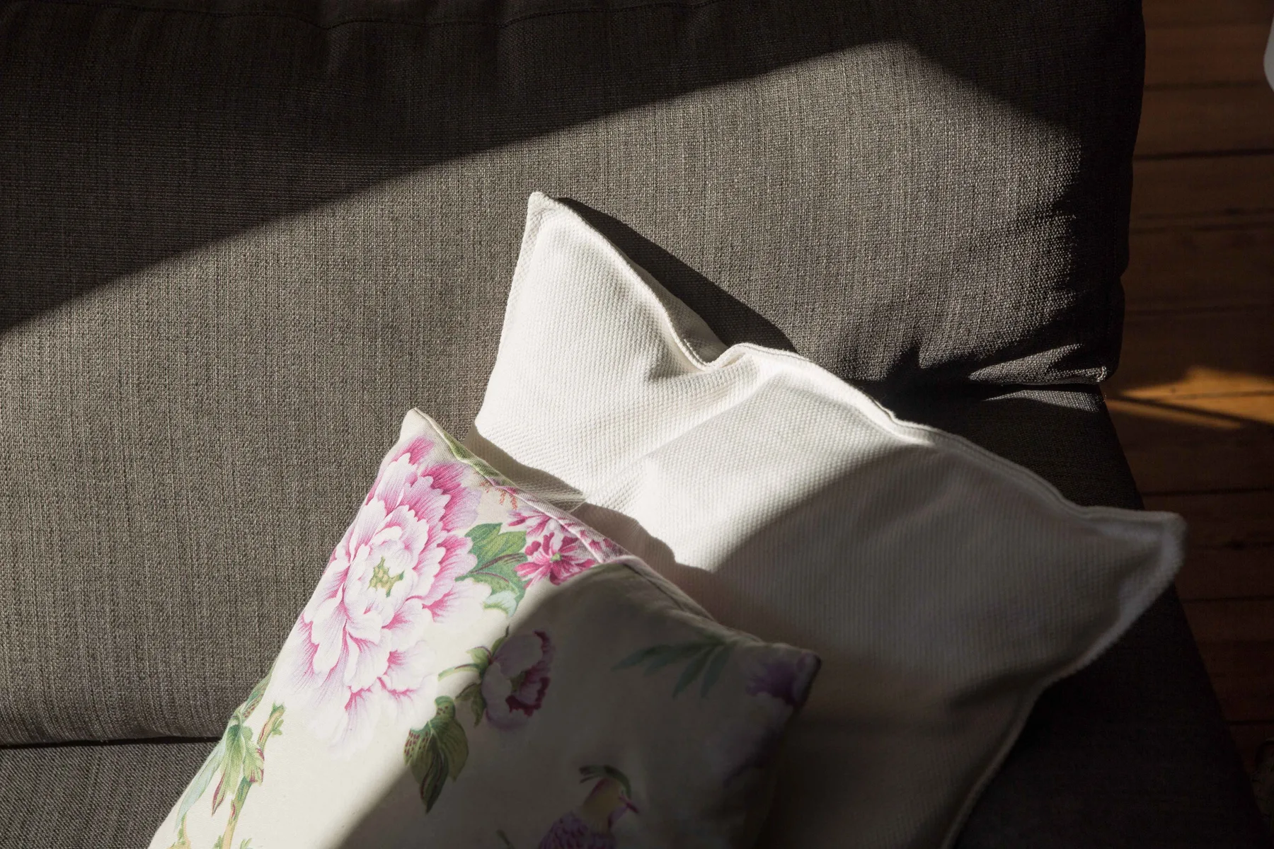 A seating area with floral and plain cushions in sunlight.