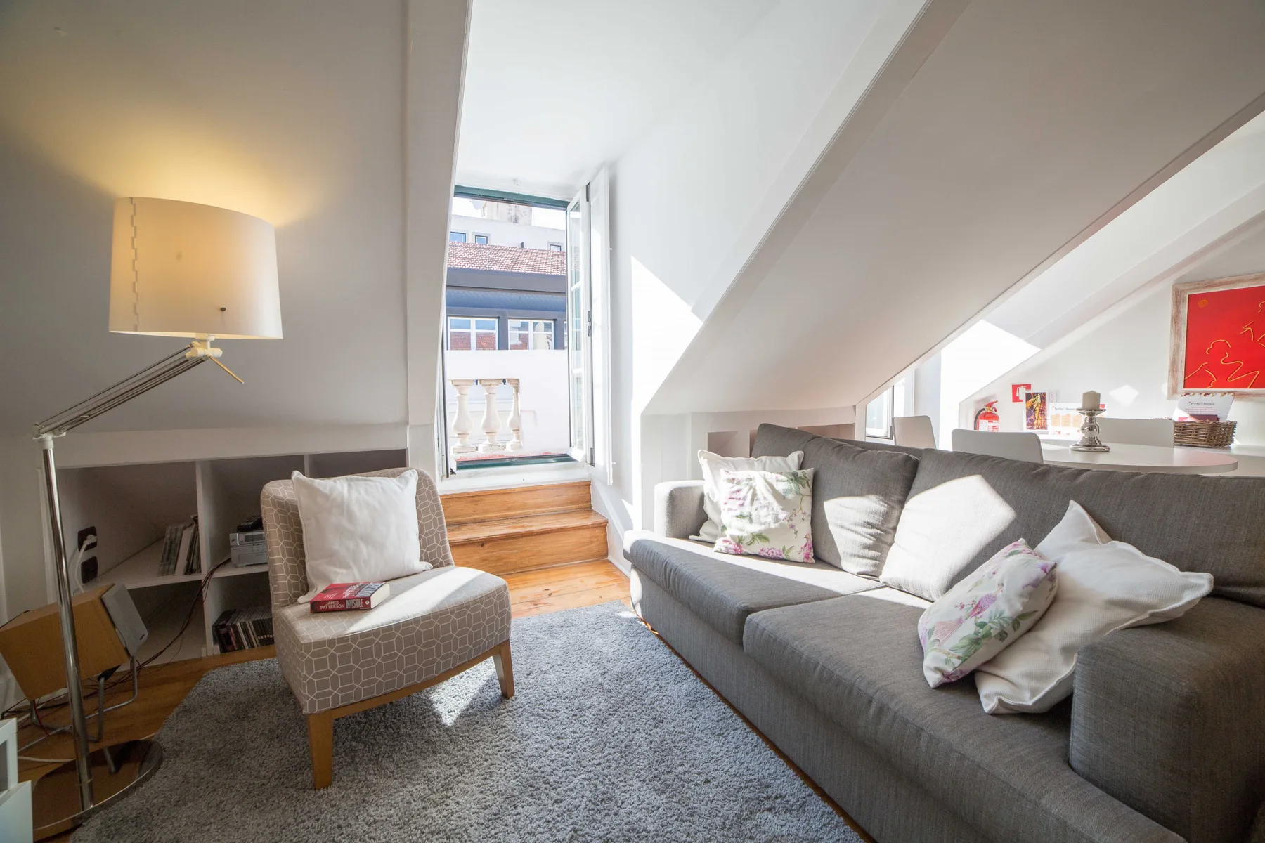 A bright attic living room with seating beside a large window.