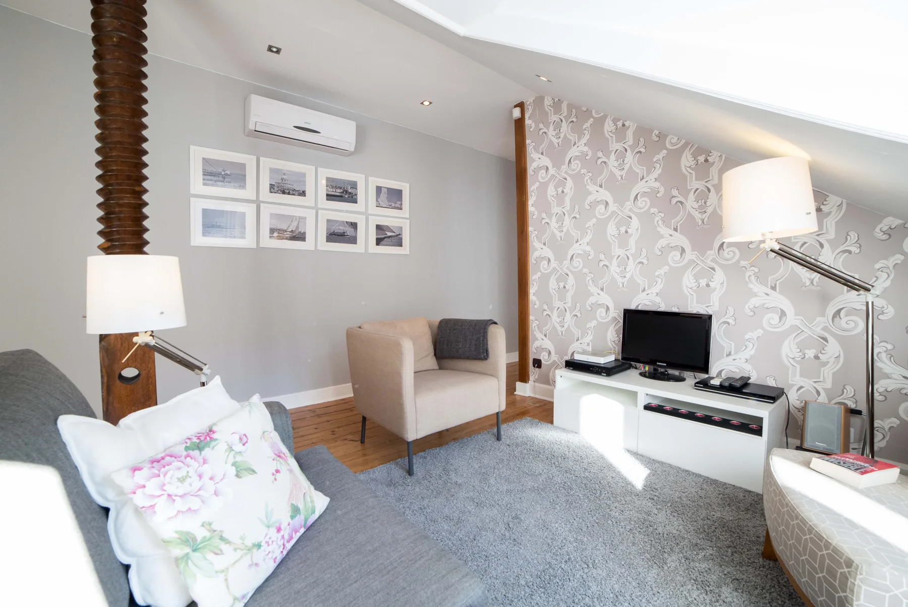 A living room with seating, a television, and patterned wallpaper.