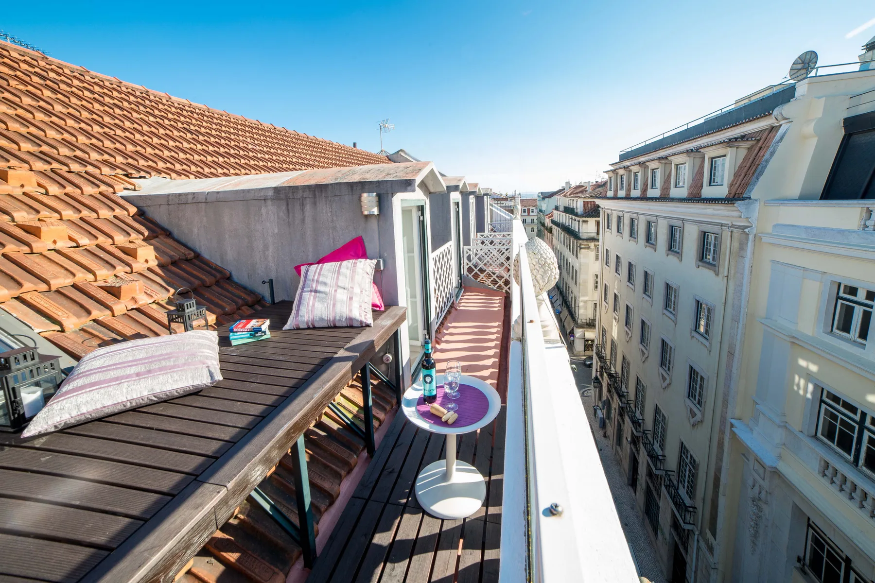 A narrow rooftop terrace with outdoor seating and views of neighboring buildings.