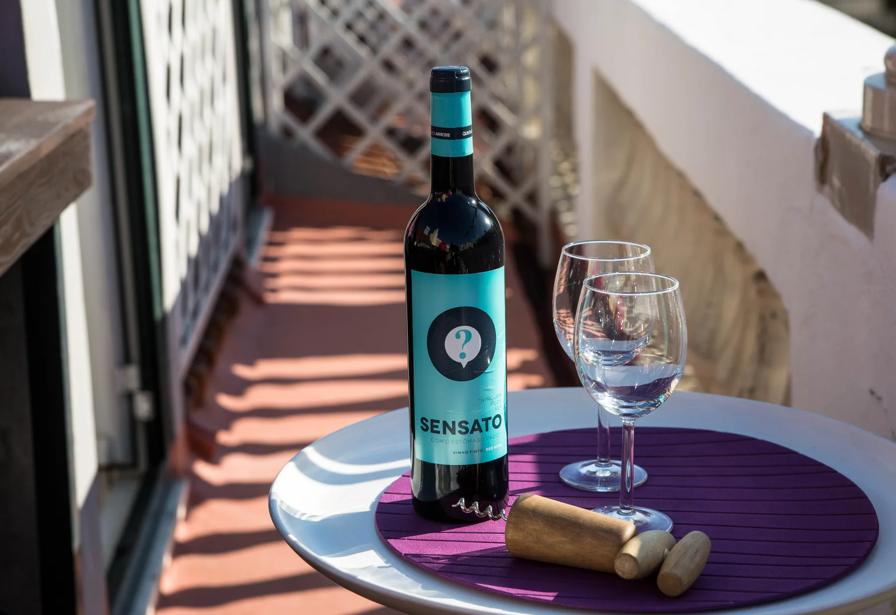 A small outdoor table holds a wine bottle and two glasses on a terrace.