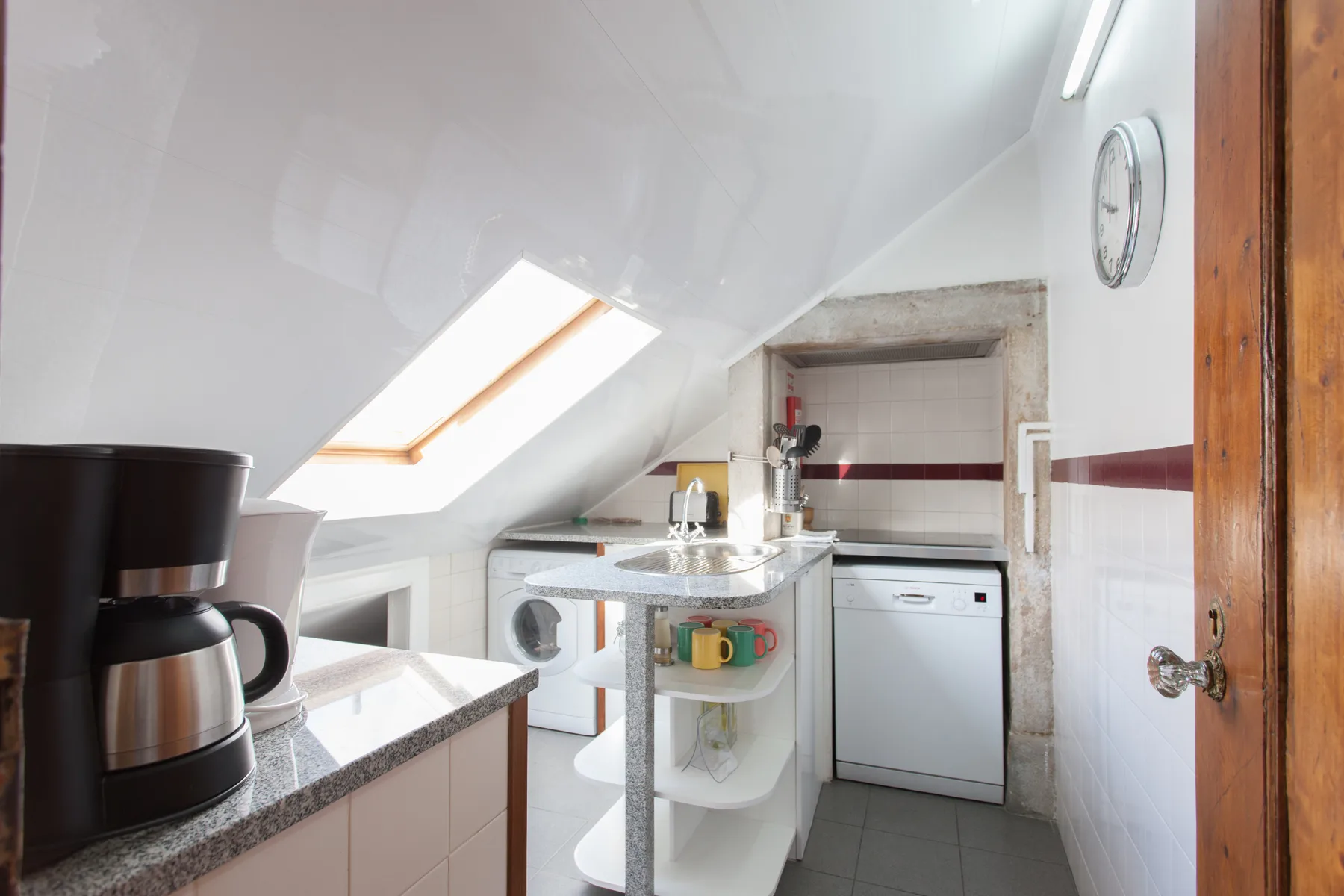 A compact kitchen with a skylight, countertop, and washing machine.