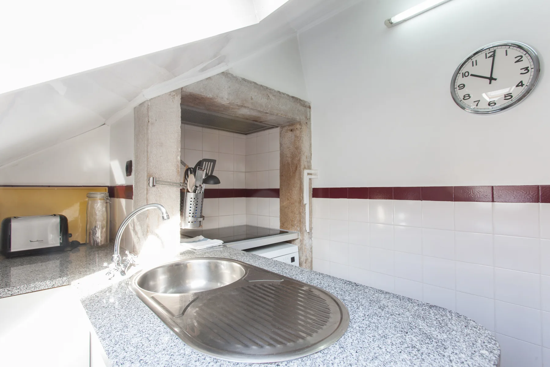 A bright kitchen with a sink, countertop, and tiled backsplash.