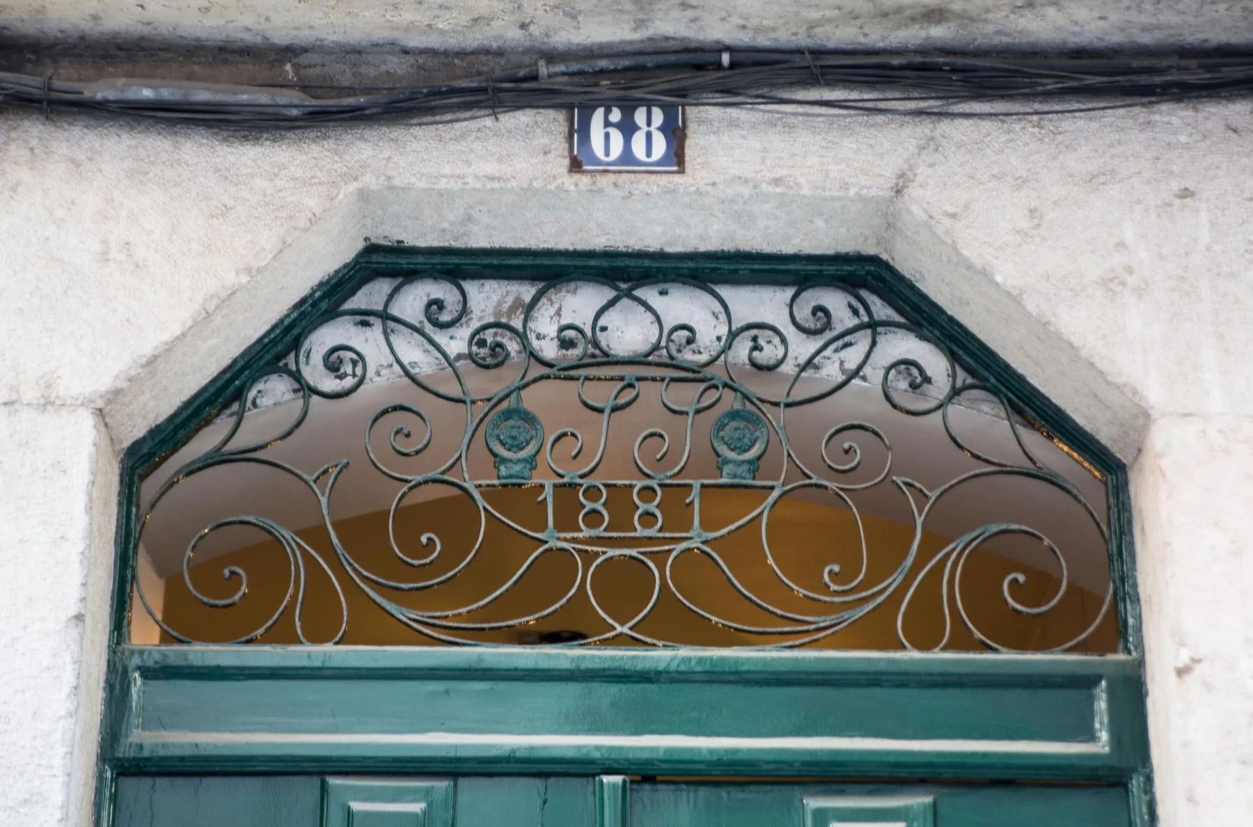 A green entrance door sits beneath an ornate wrought-iron transom.