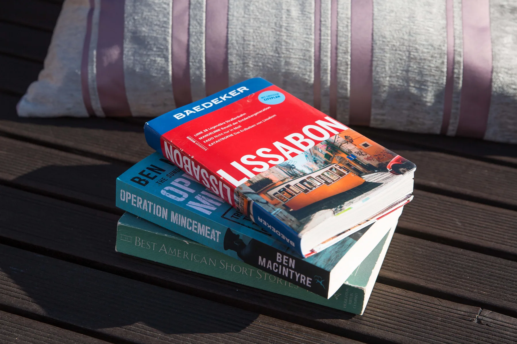 Travel guidebooks about Lisbon rest on a dark slatted table.