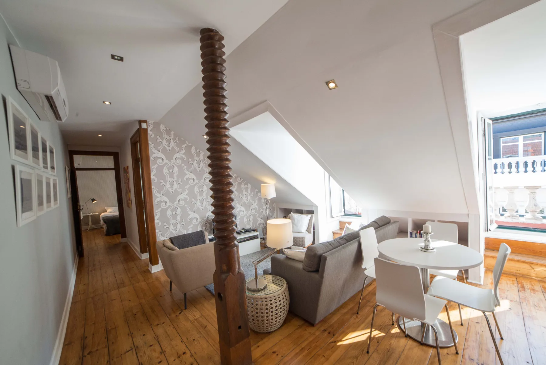 A bright living and dining area with seating, a table, and a sloped ceiling.
